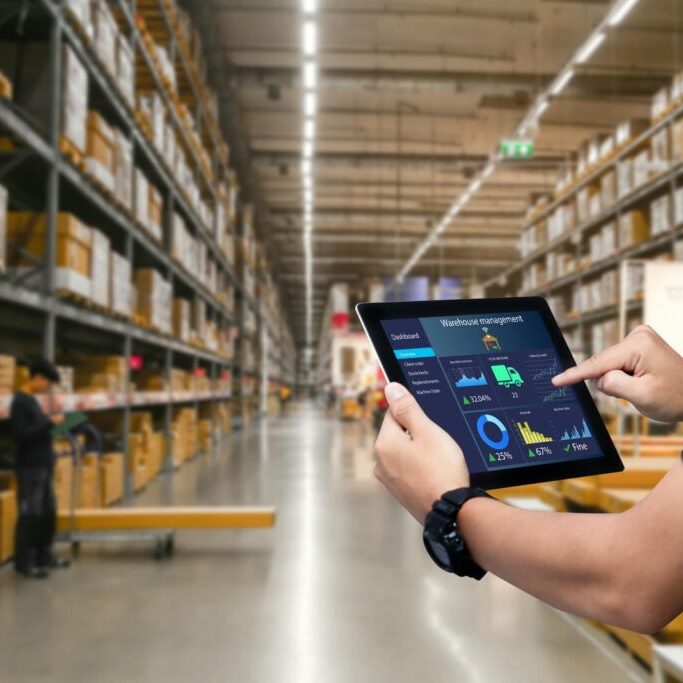 Smart warehouse management system.Worker hands holding tablet on blurred warehouse as background